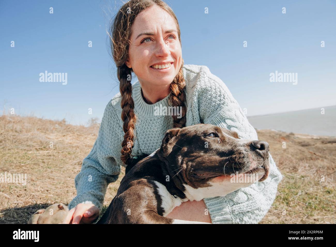 Donna felice con un cane sulla collina durante il giorno di sole Foto Stock