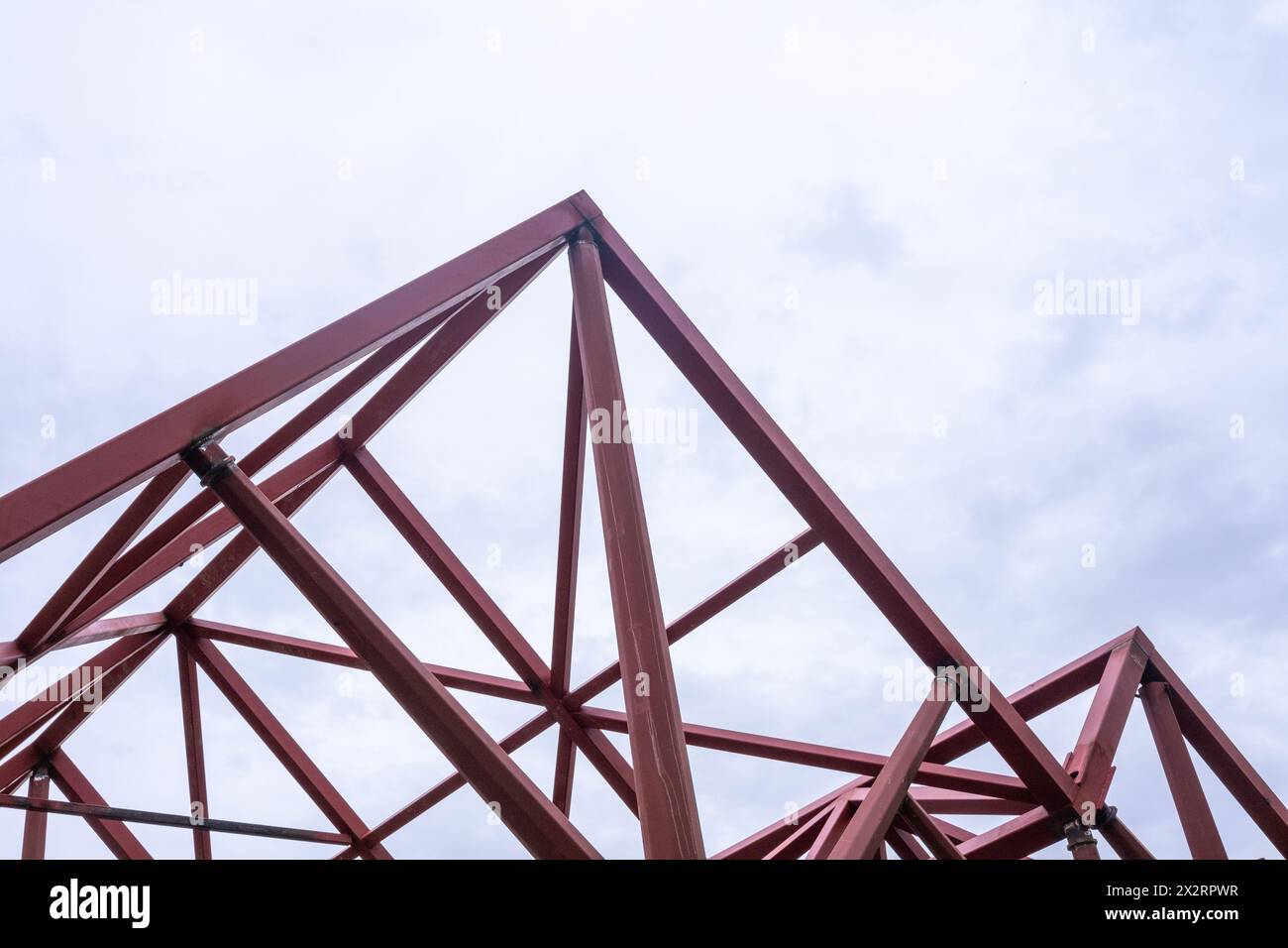 Composizione geometrica di travi metalliche rosse in una costruzione moderna contro un cielo limpido con spazio di copia Foto Stock