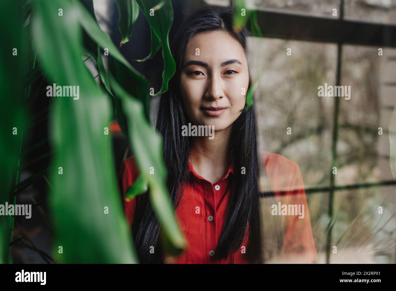 Una giovane donna fotografata attraverso una finestra di vetro Foto Stock