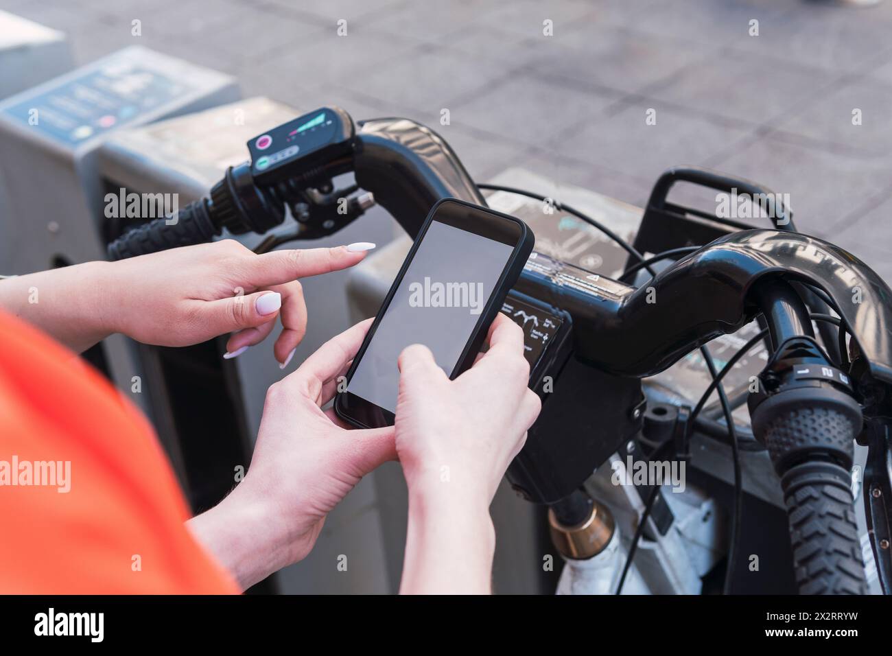Amici che eseguono la scansione del codice a barre per noleggiare un ciclo elettrico in città Foto Stock