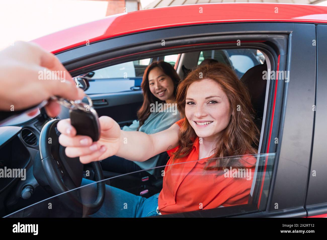 Donna sorridente che prende la chiave dell'auto dal venditore Foto Stock