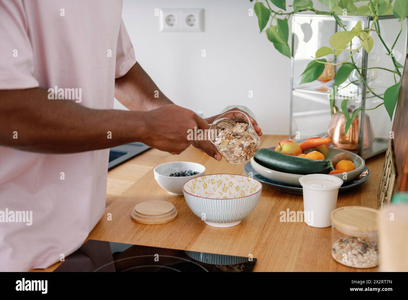 Uomo che prepara i cereali da colazione nel recipiente al banco della cucina Foto Stock