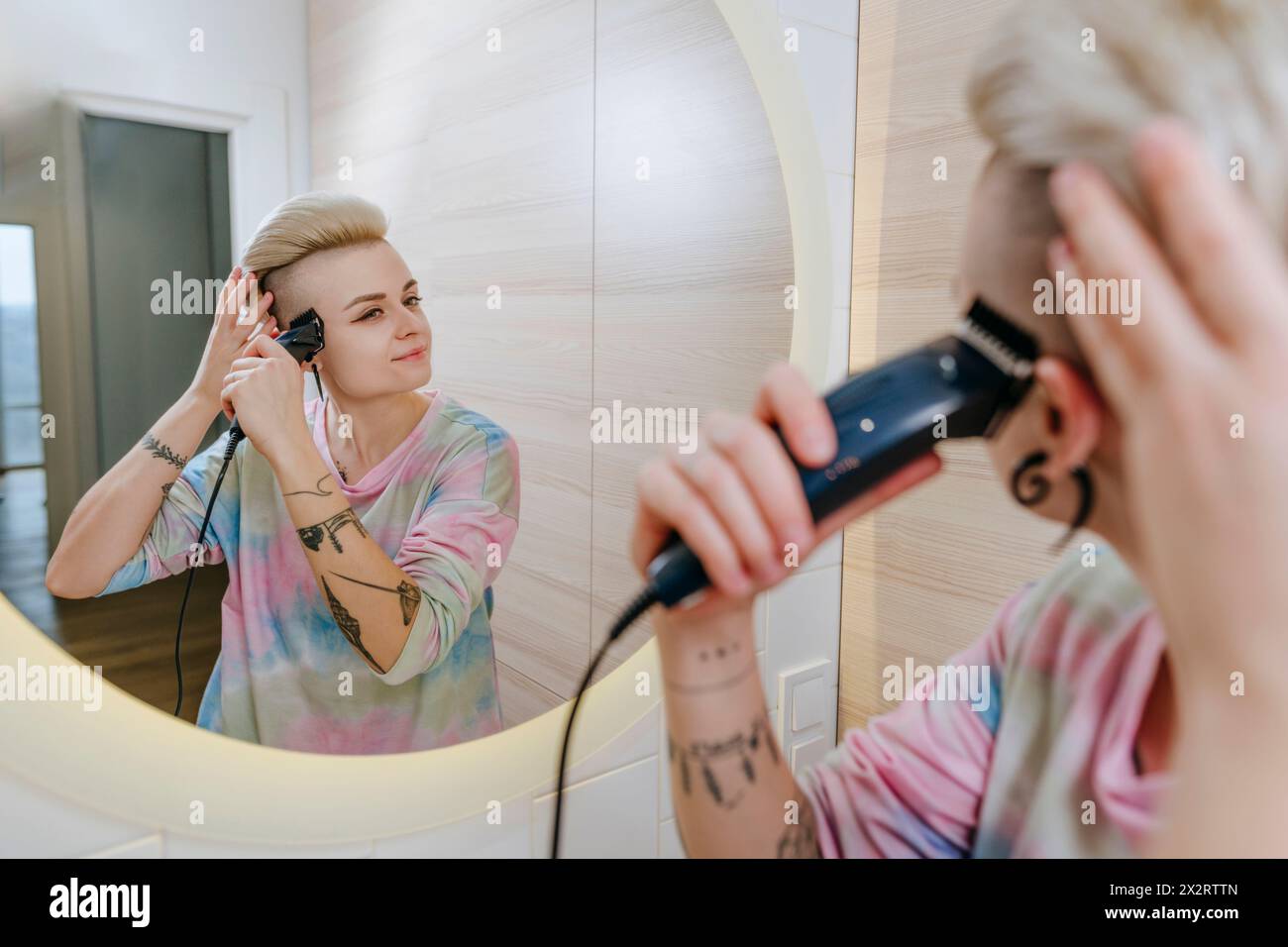 Donna che taglia i capelli utilizzando un rasoio elettrico a casa Foto Stock