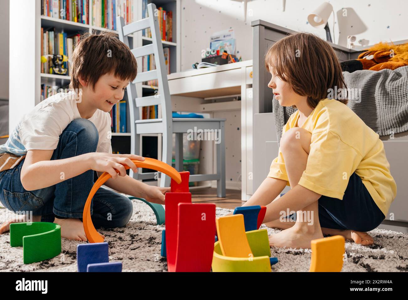 Fratelli che giocano con giocattoli in legno multicolore a casa Foto Stock