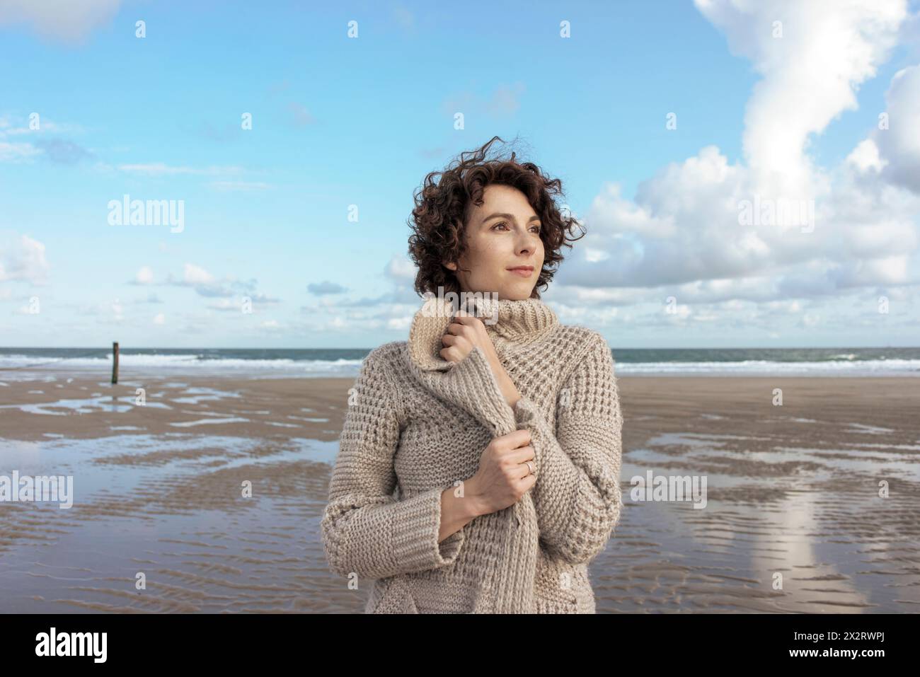 Bella donna che indossa un maglione cardigan in piedi in spiaggia Foto Stock