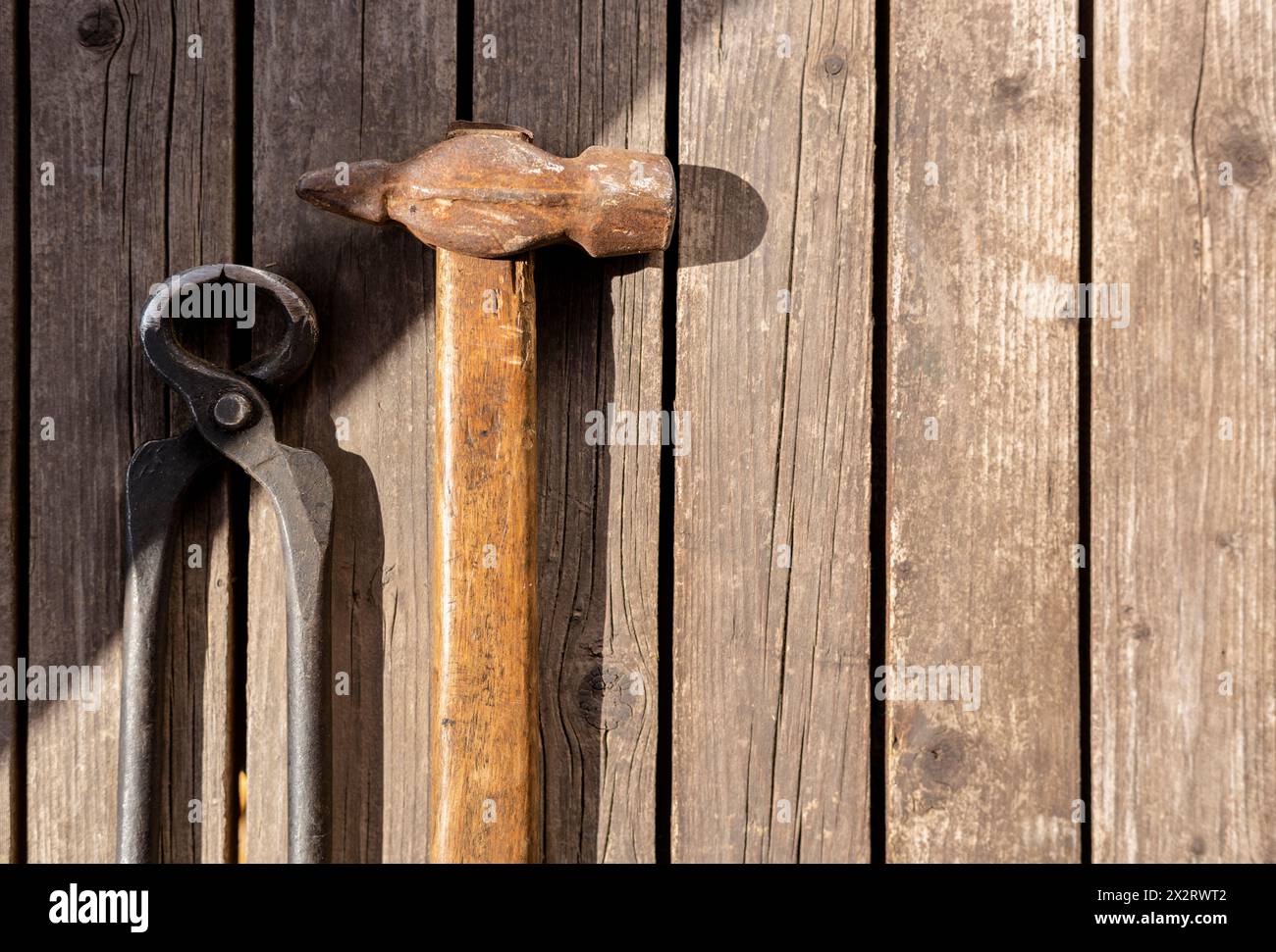 Vecchio martello e pinze appoggiati su un tavolo di legno Foto Stock