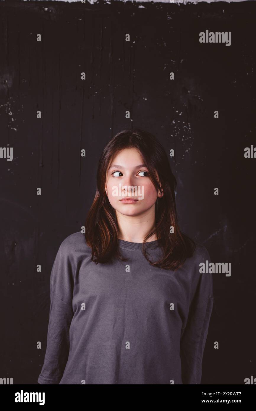 Ragazza con uno sguardo laterale davanti allo sfondo nero Foto Stock