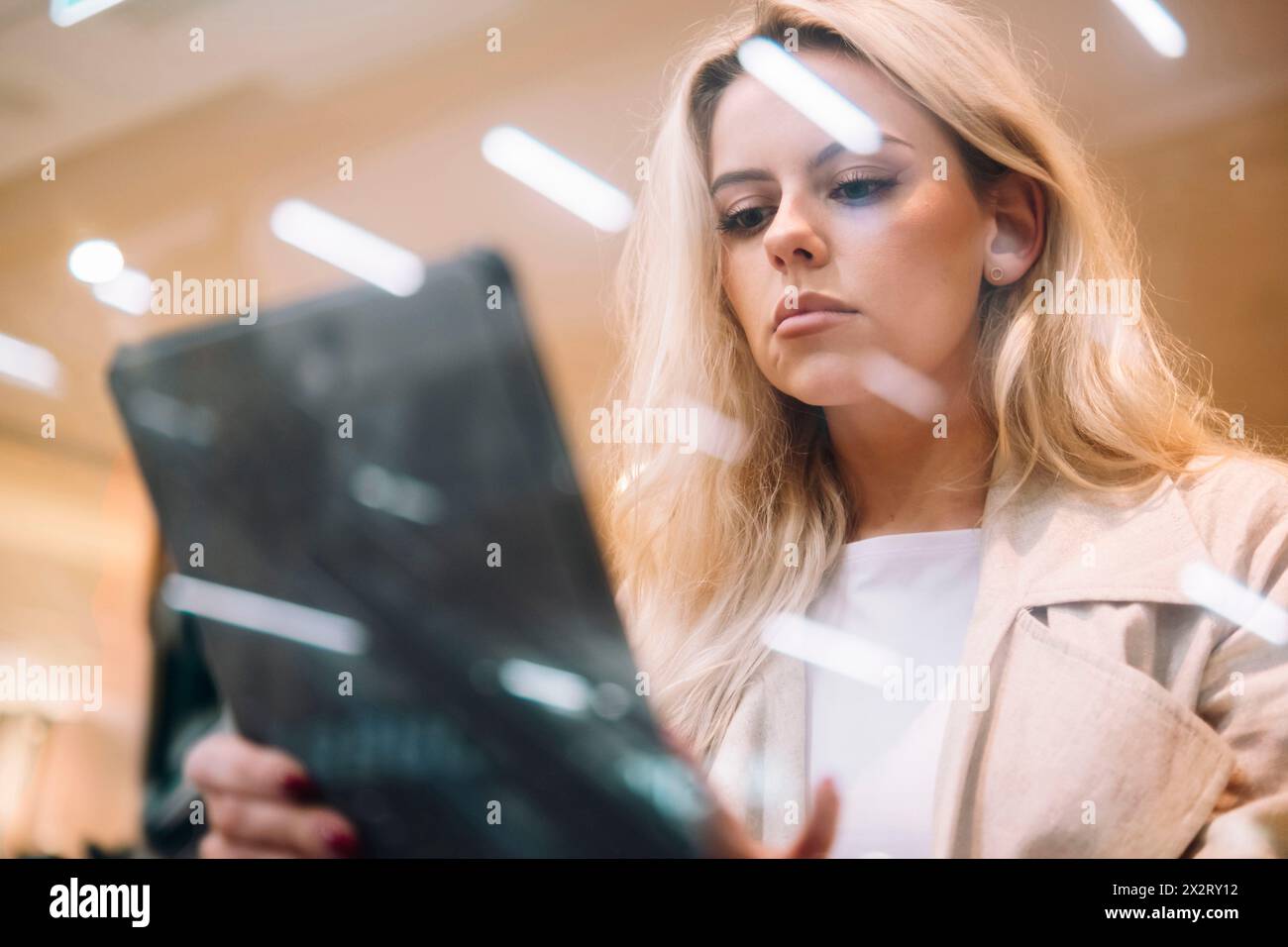 Giovane donna che usa un tablet PC visto attraverso il vetro Foto Stock
