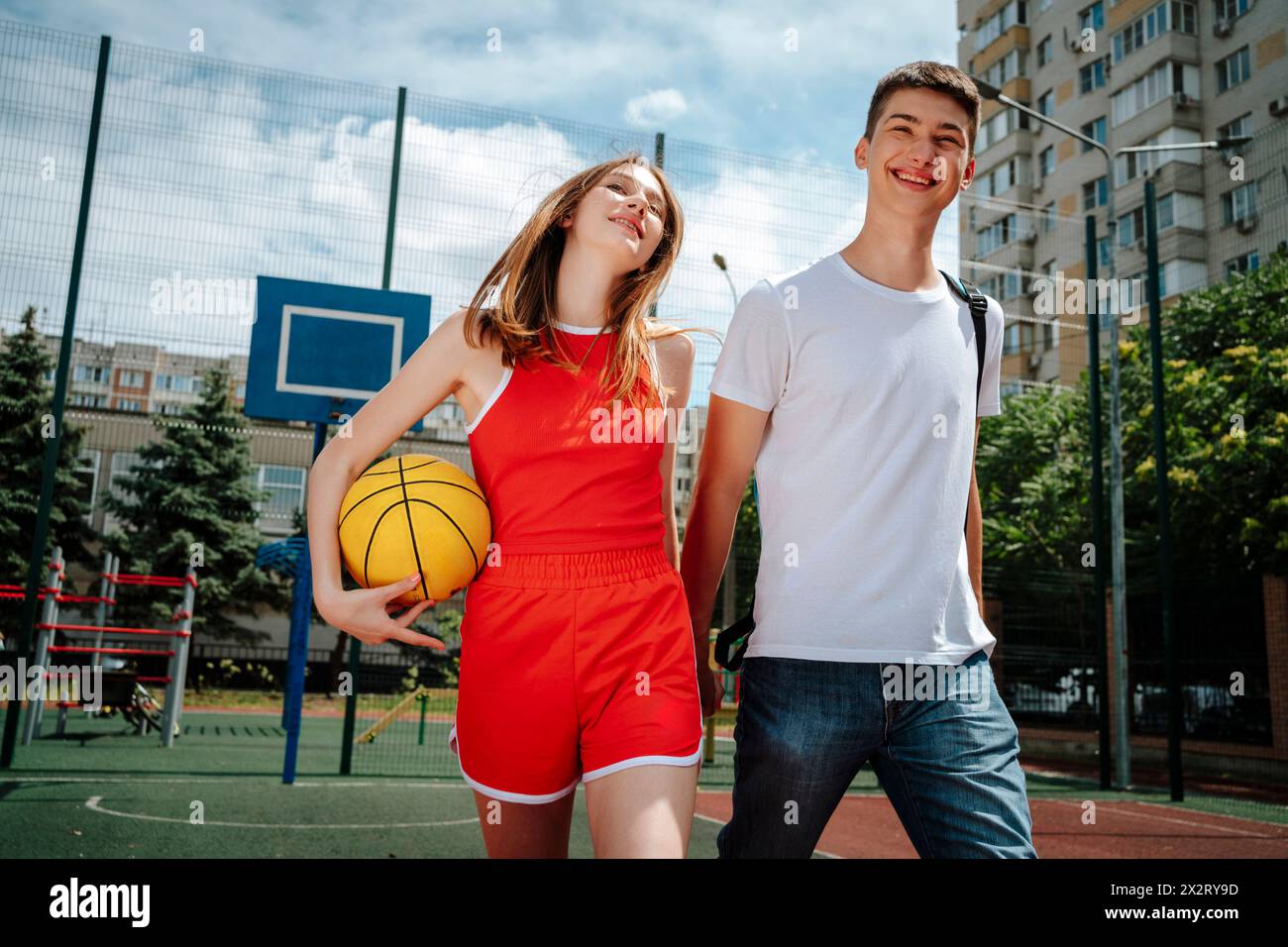 Amici di scuola che si tengono per mano e camminano nel cortile della scuola Foto Stock