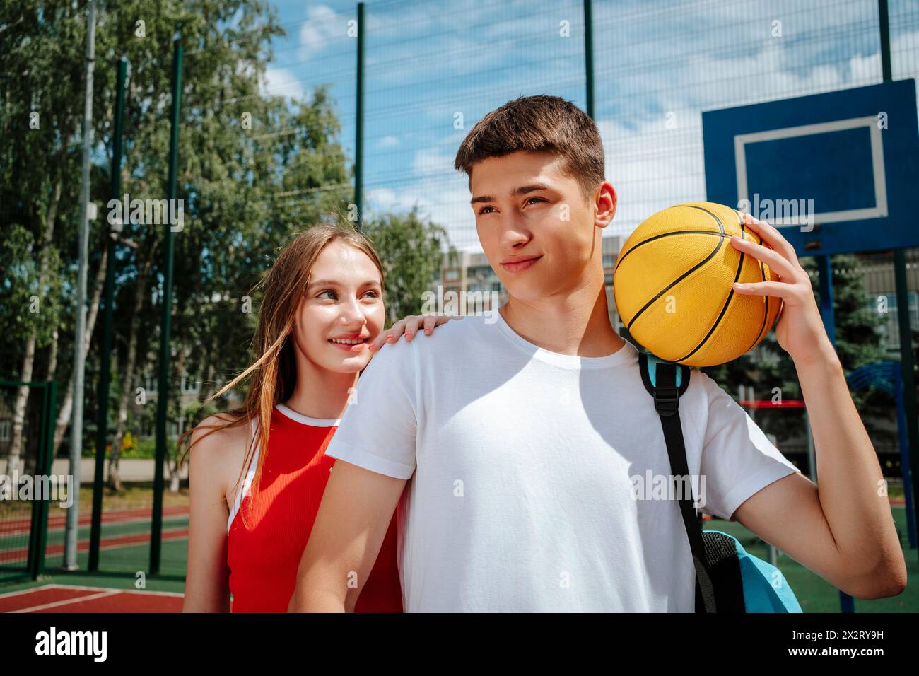 Ragazzo sicuro che tiene la palla vicino ad un amico nel cortile della scuola Foto Stock