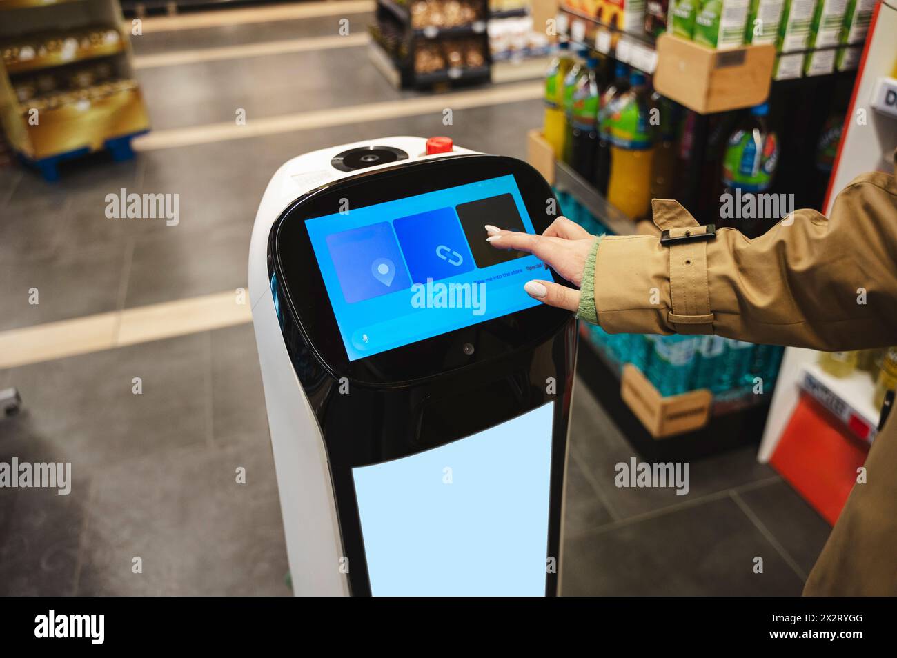 Donna che interagisce con l'assistente robotica al supermercato Foto Stock