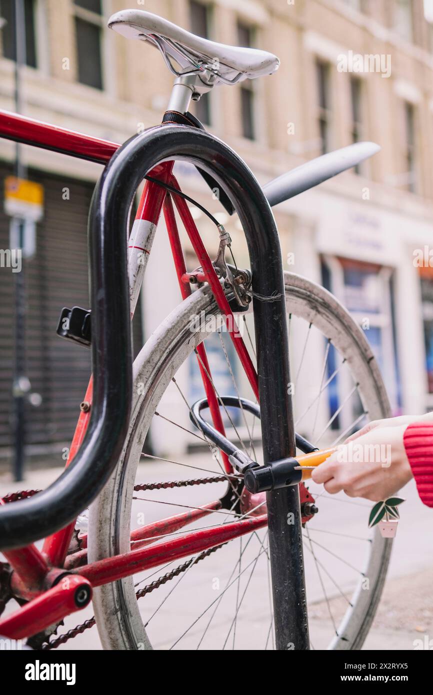 Mano di donna che blocca la bicicletta al parcheggio Foto Stock