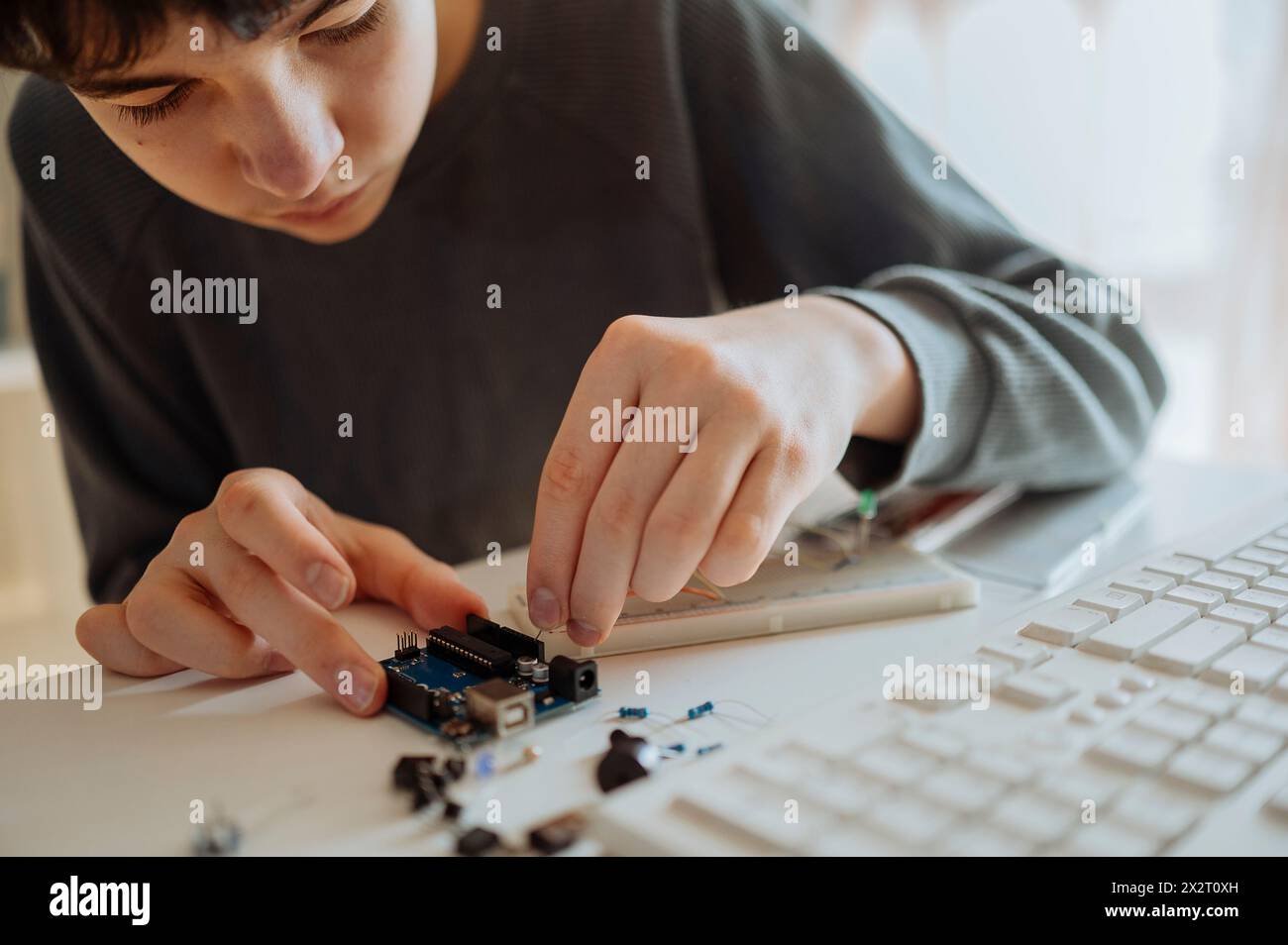 Adolescente che regola il componente elettrico vicino alla tastiera a casa Foto Stock