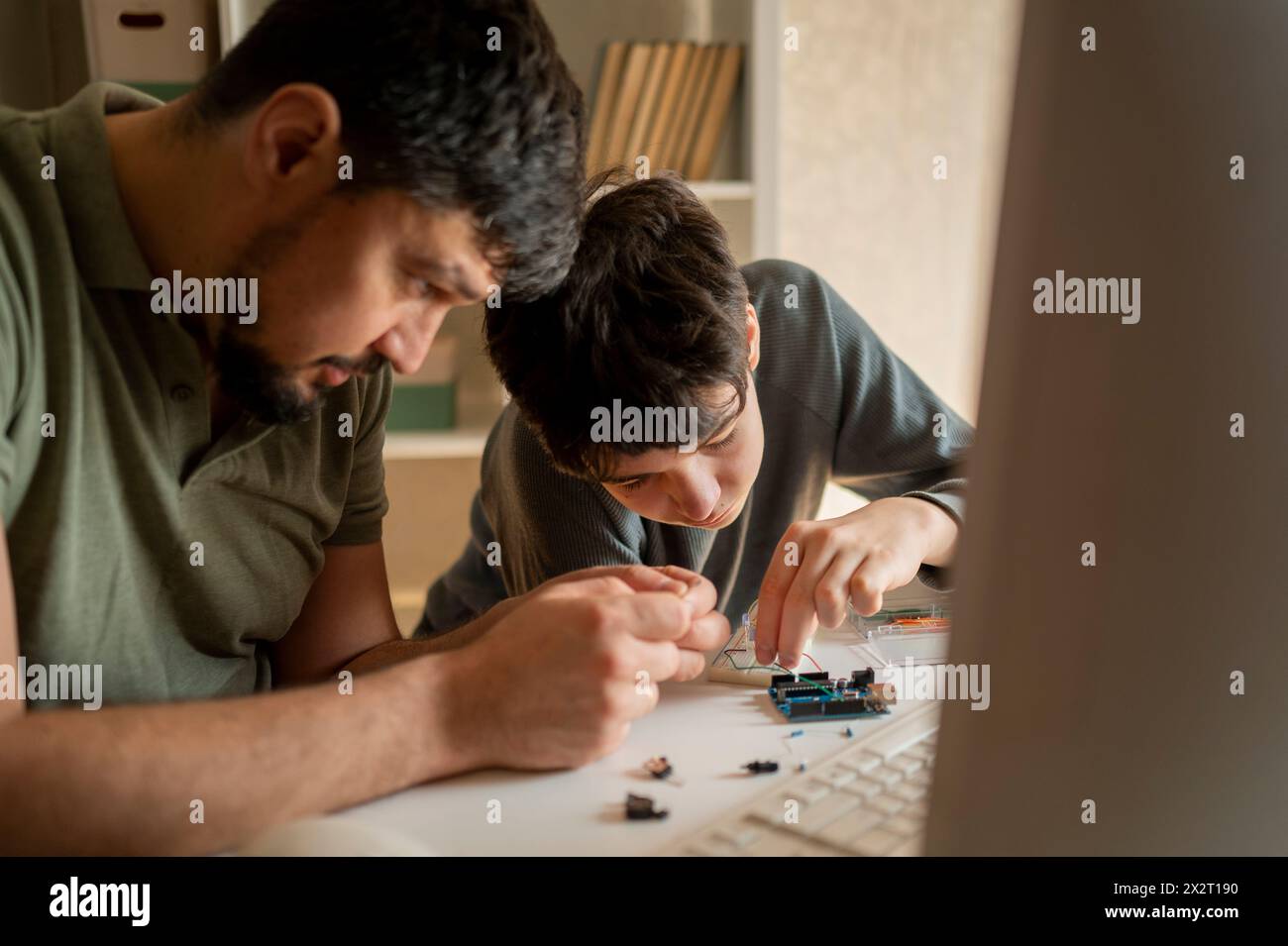 Ragazzo che regola le apparecchiature elettriche vicino al padre a casa Foto Stock