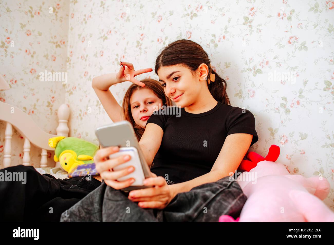 Ragazza che fa selfie con un amico che mostra un segno di pace a casa Foto Stock