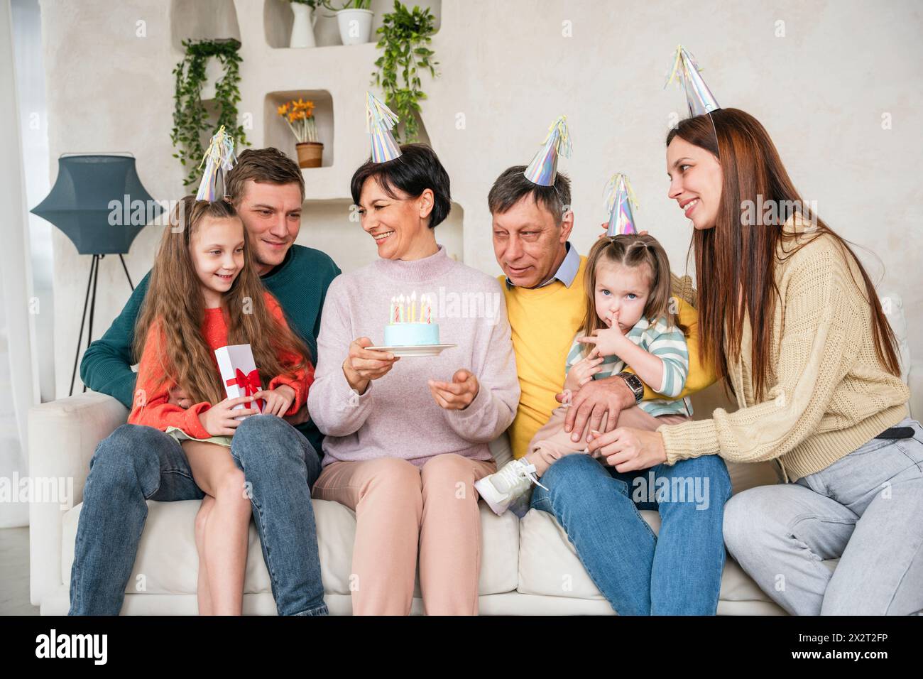 Famiglia in cappelli da festa per festeggiare il compleanno insieme a casa Foto Stock