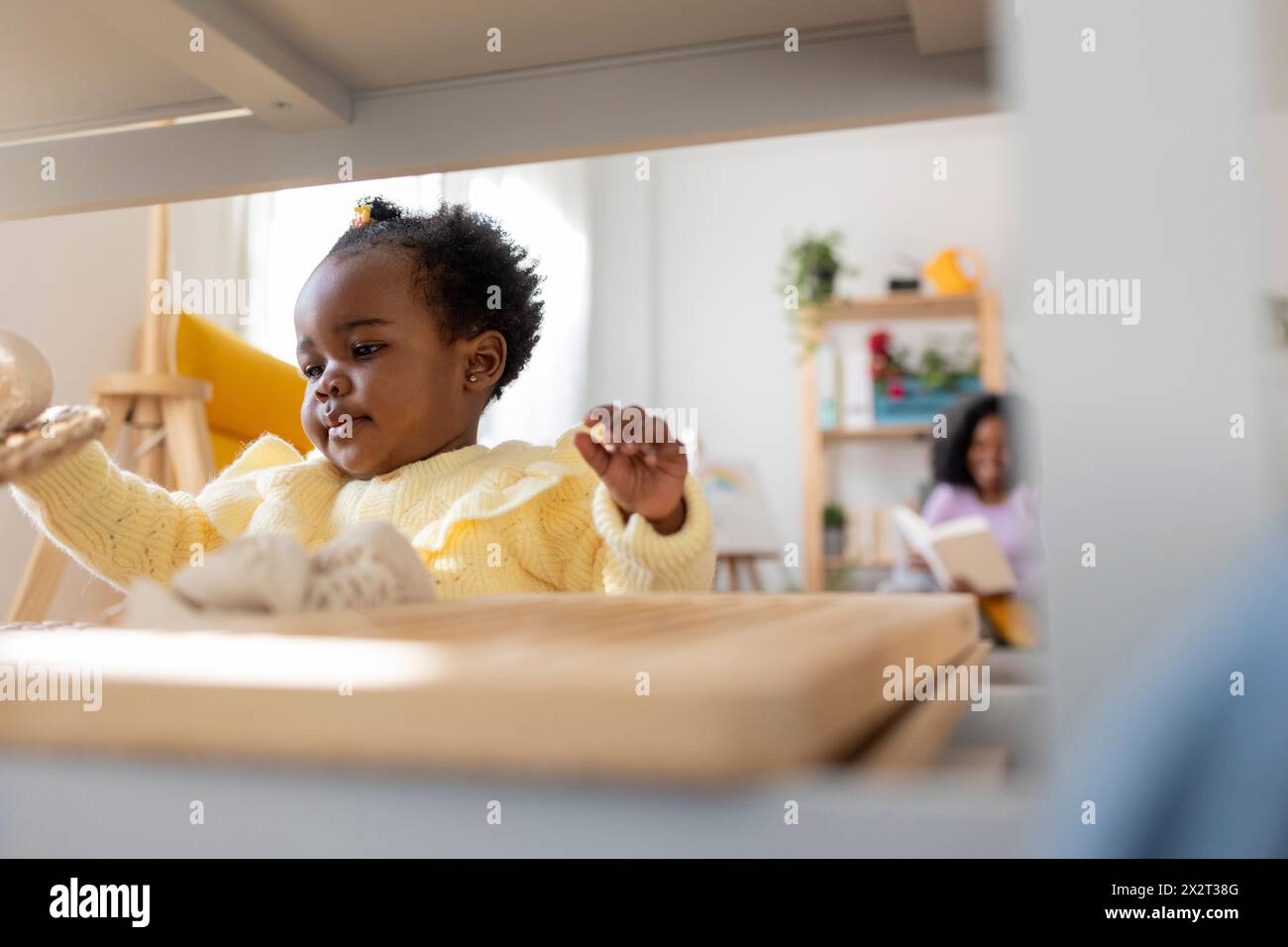 Simpatica bimba che gioca su un rack nel soggiorno di casa Foto Stock