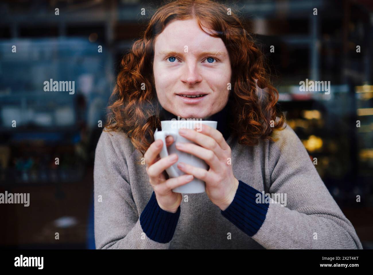 Uomo sorridente che tiene una tazza di caffè al bar Foto Stock