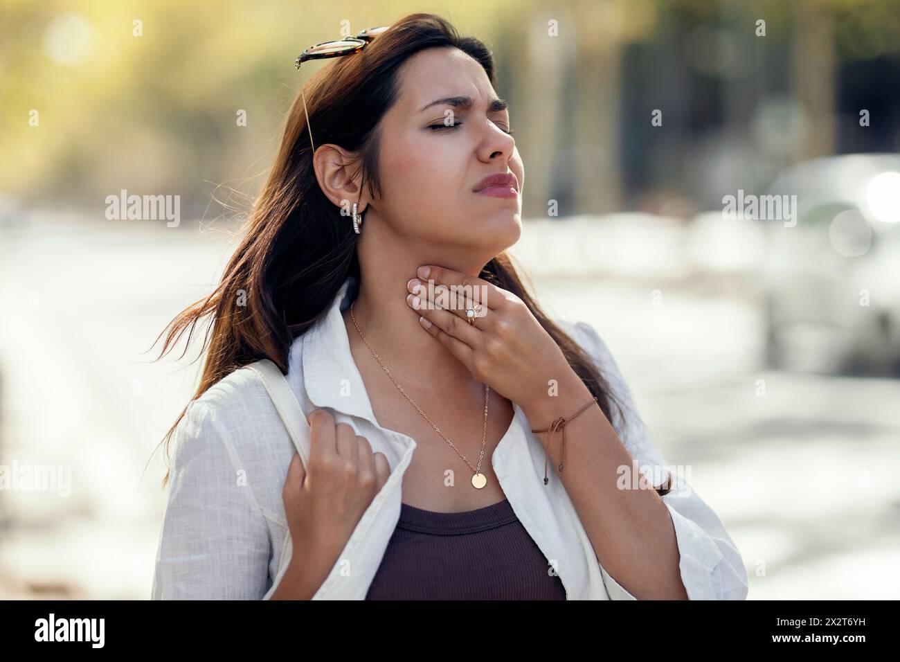 Giovane donna con allergia alla gola in strada Foto Stock