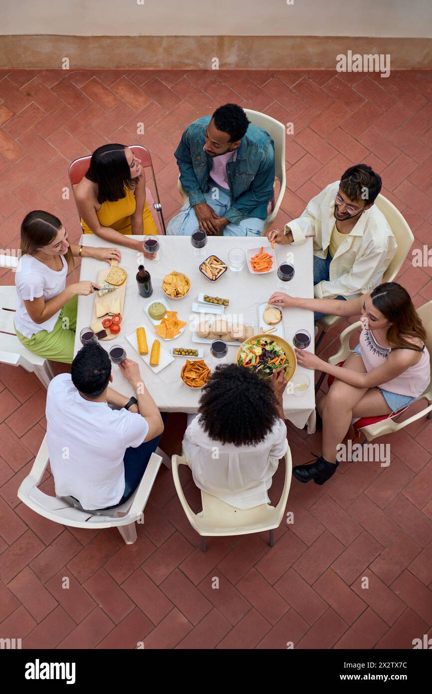 Vista dall'alto di un incontro di persone intorno a un tavolo con bicchieri di vino e cibo Foto Stock