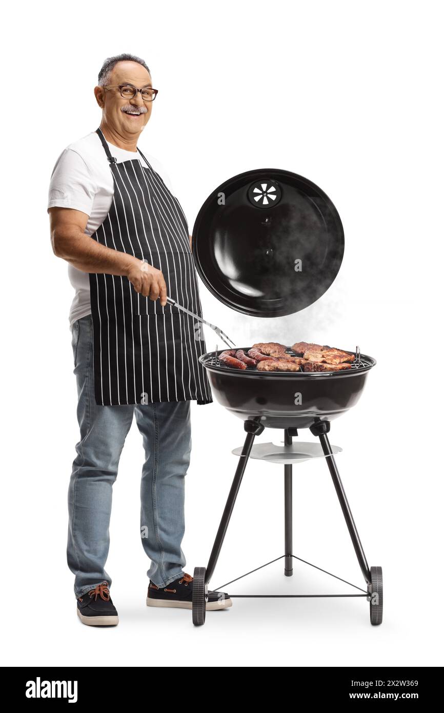Uomo maturo che prepara carne su un barbecue isolato su sfondo bianco Foto Stock