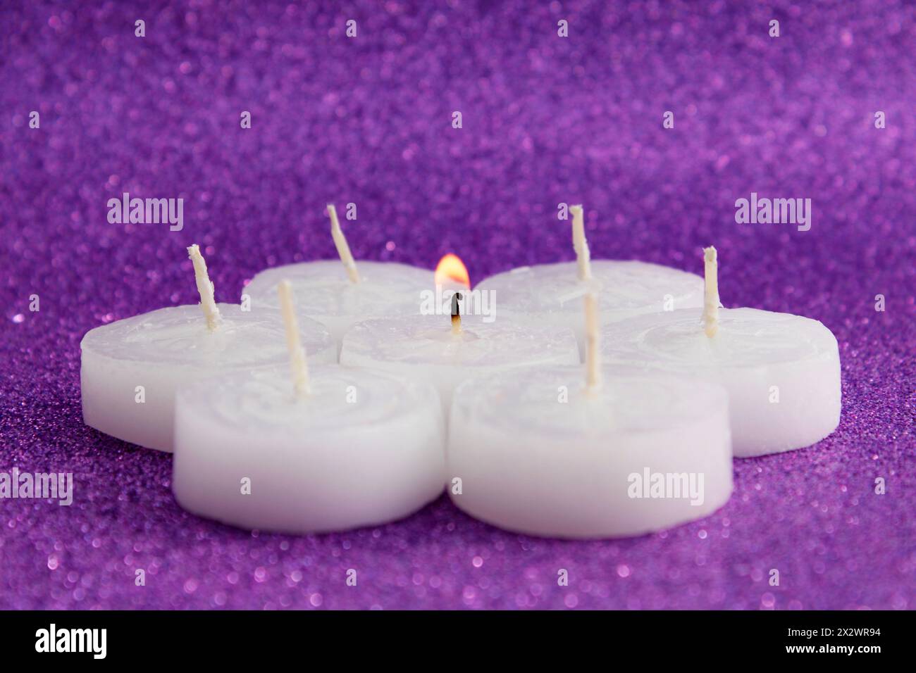 Candele accese al centro circondate da diverse candele spente Foto Stock