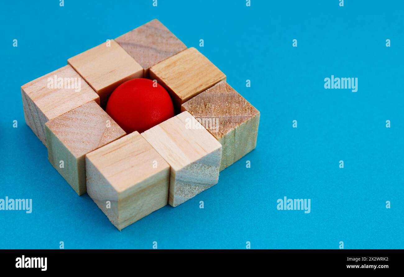 Sfera di legno circondata da cubi che entrano in uno spazio quadrato Foto Stock