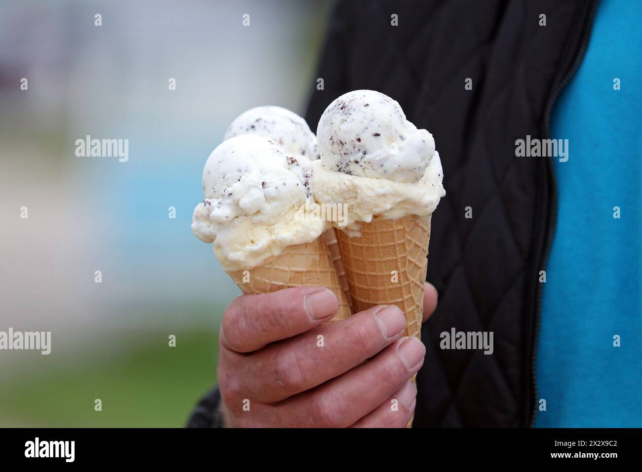 01.09.2023, Iffezheim, Baden-Wuerttemberg, Germania - primo piano: L'uomo ha in mano tre coni di gelato. 00S230901D849CAROEX.JPG [MODELLO R Foto Stock