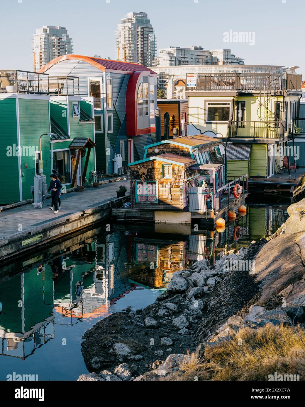 Victoria, Canada - 17 marzo 2024: Una fila di case galleggianti colorate al Fisherman's Wharf, che catturano la splendida luce del sole riflessa dal mare. Foto Stock