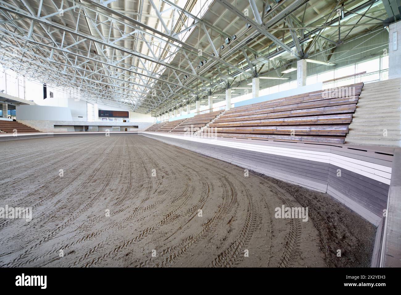 Piccolo stadio coperto con lunghe panche e sabbia rivestita per le corse di cavalli. Foto Stock
