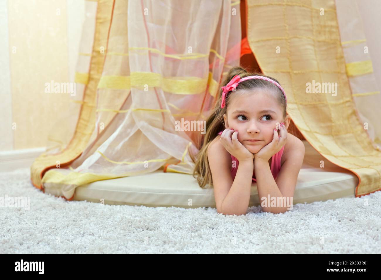 La bambina giace sullo stomaco, con le mani sotto il baldacchino Foto Stock