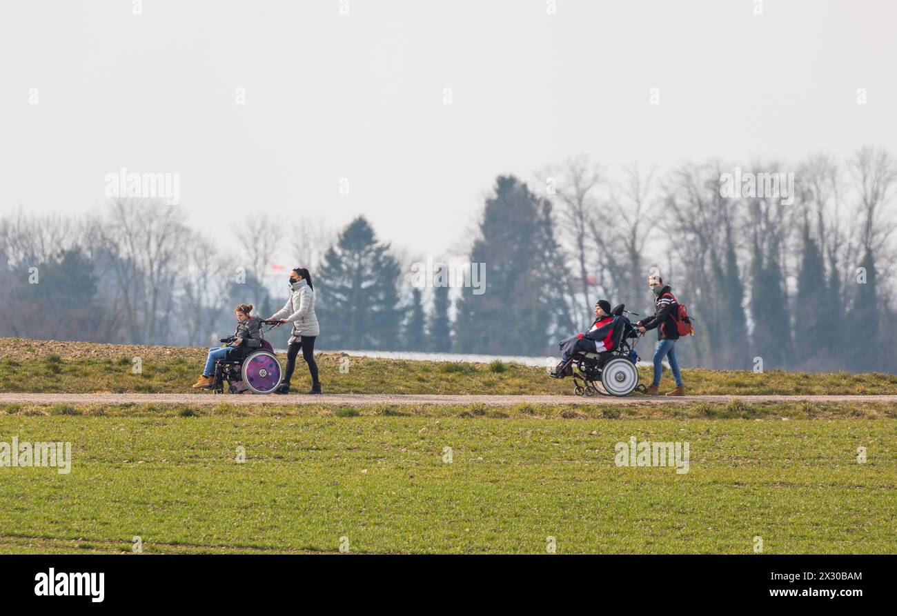 Zürich, Schweiz - 12. März 2022: Betreuer sind mit Menschen mit einer körperlichen Beeinträchtigung mit dem Rollstuhl unterwegs. Die ersten wärmenden Foto Stock