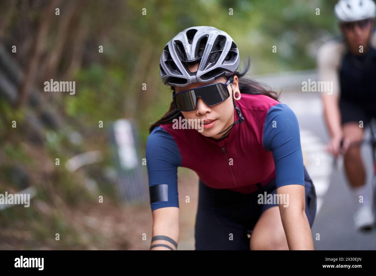 giovane donna asiatica ciclista donna che cavalca in bicicletta all'aperto su strada rurale Foto Stock