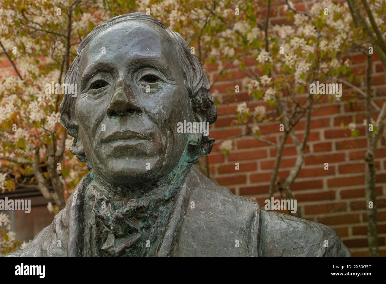 Statua in bronzo di H C Andersen con sfondo di fiori e mattoni, Odense, Danimarca, 19 aprile 2024 Foto Stock