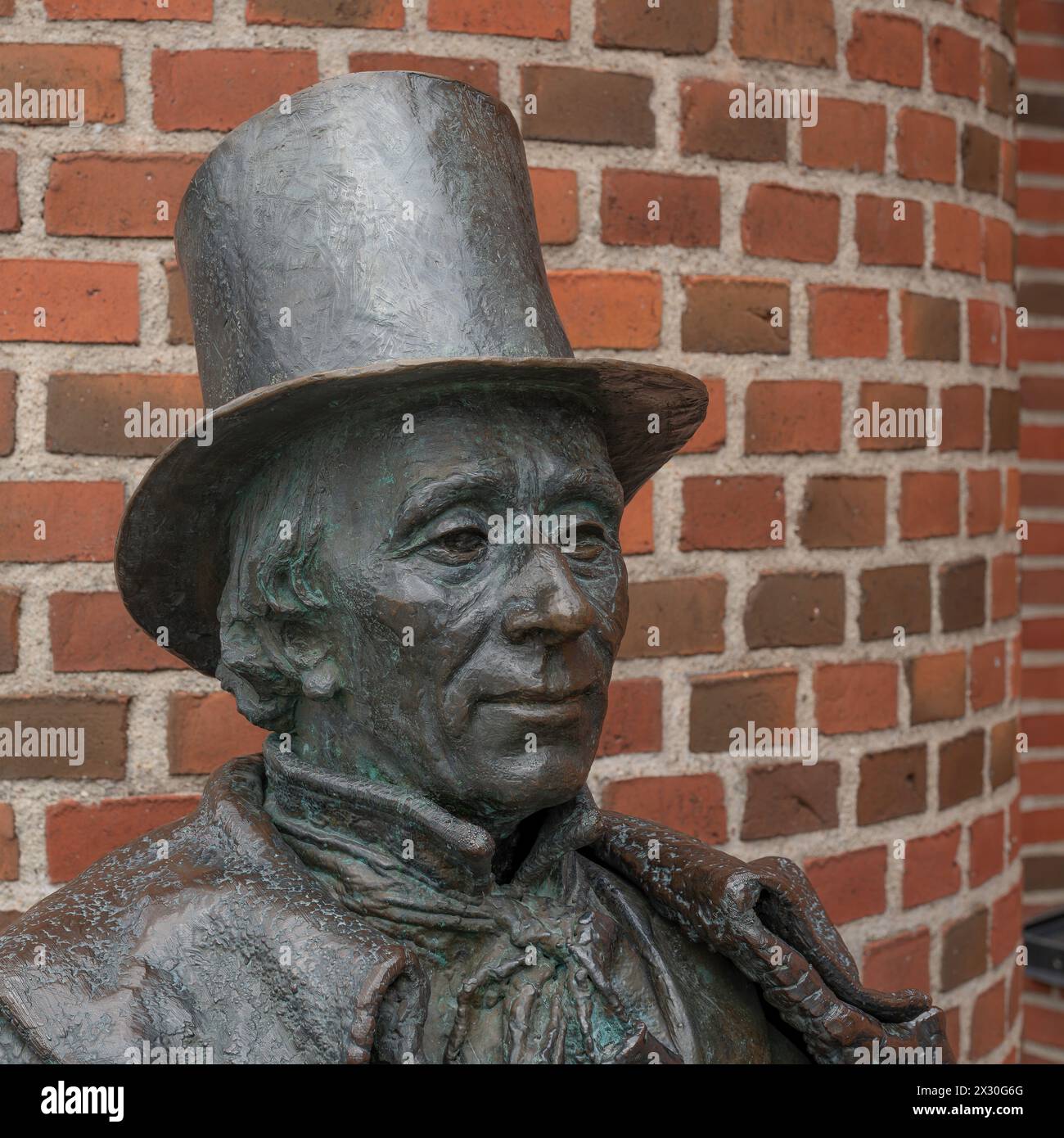 Statua in bronzo di H C Andersen in cappello contro un muro di mattoni rossi, Odense, Danimarca, 19 aprile 2024 Foto Stock