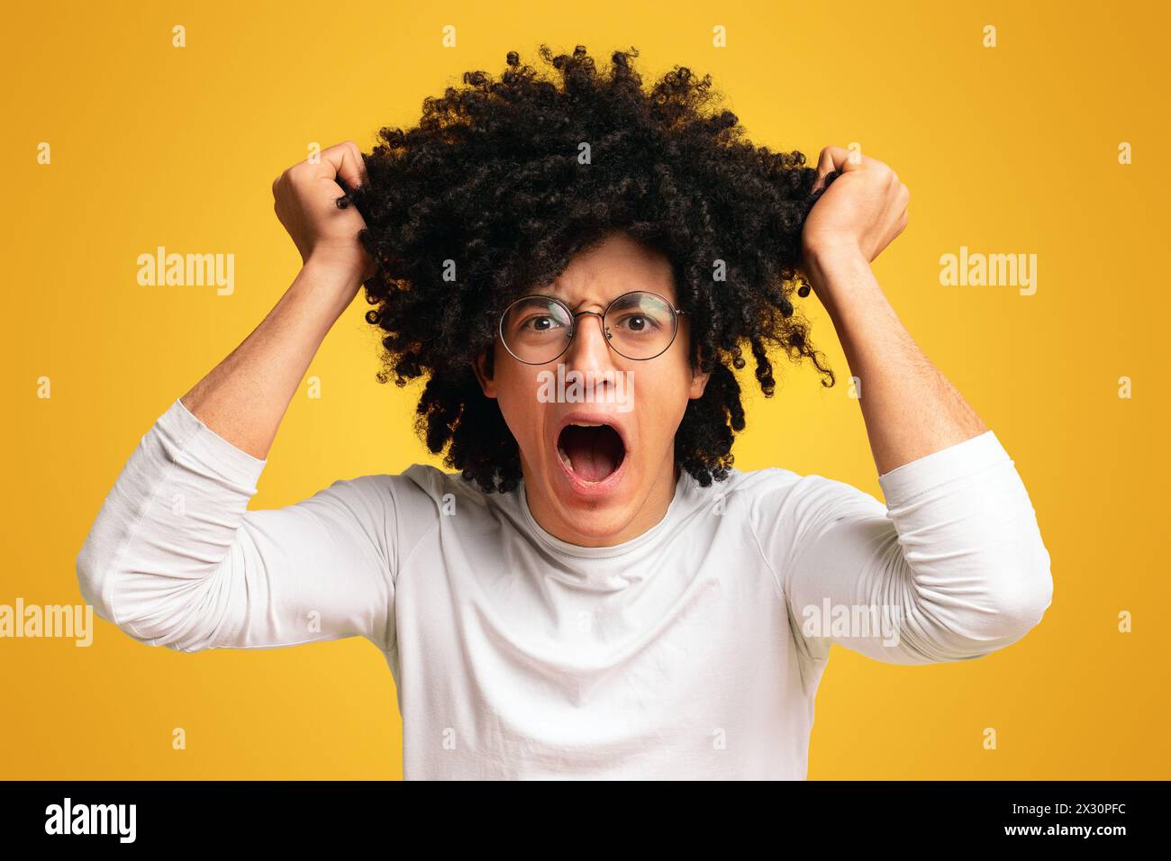 Emotional uomo nero nella disperazione tirando fuori i suoi capelli Foto Stock