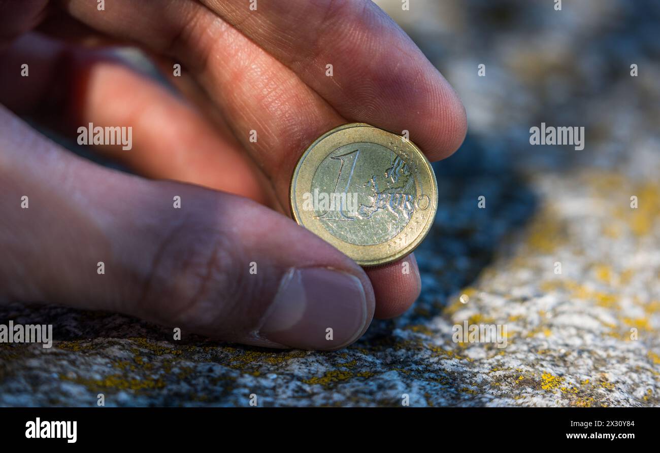 Ein junger Mann zeigt eine ein Euro Münze. (Romanshorn, Svizzera, 02.07.2022) Foto Stock