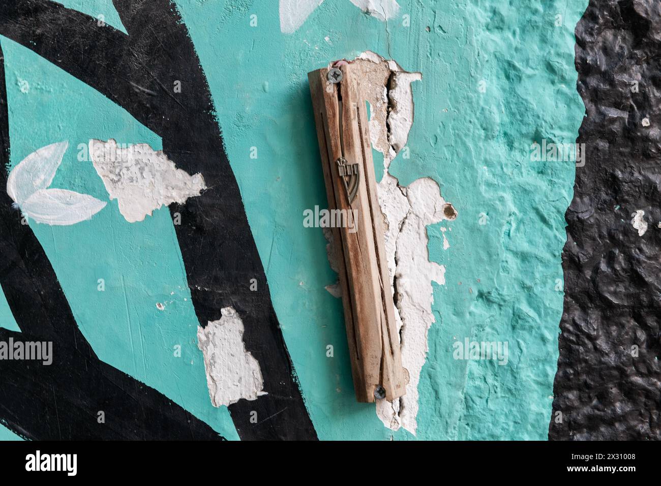 Una mezuzah di legno incrinata attaccata ad una porta su un vecchio edificio dipinto di colori a Gerusalemme. Foto Stock