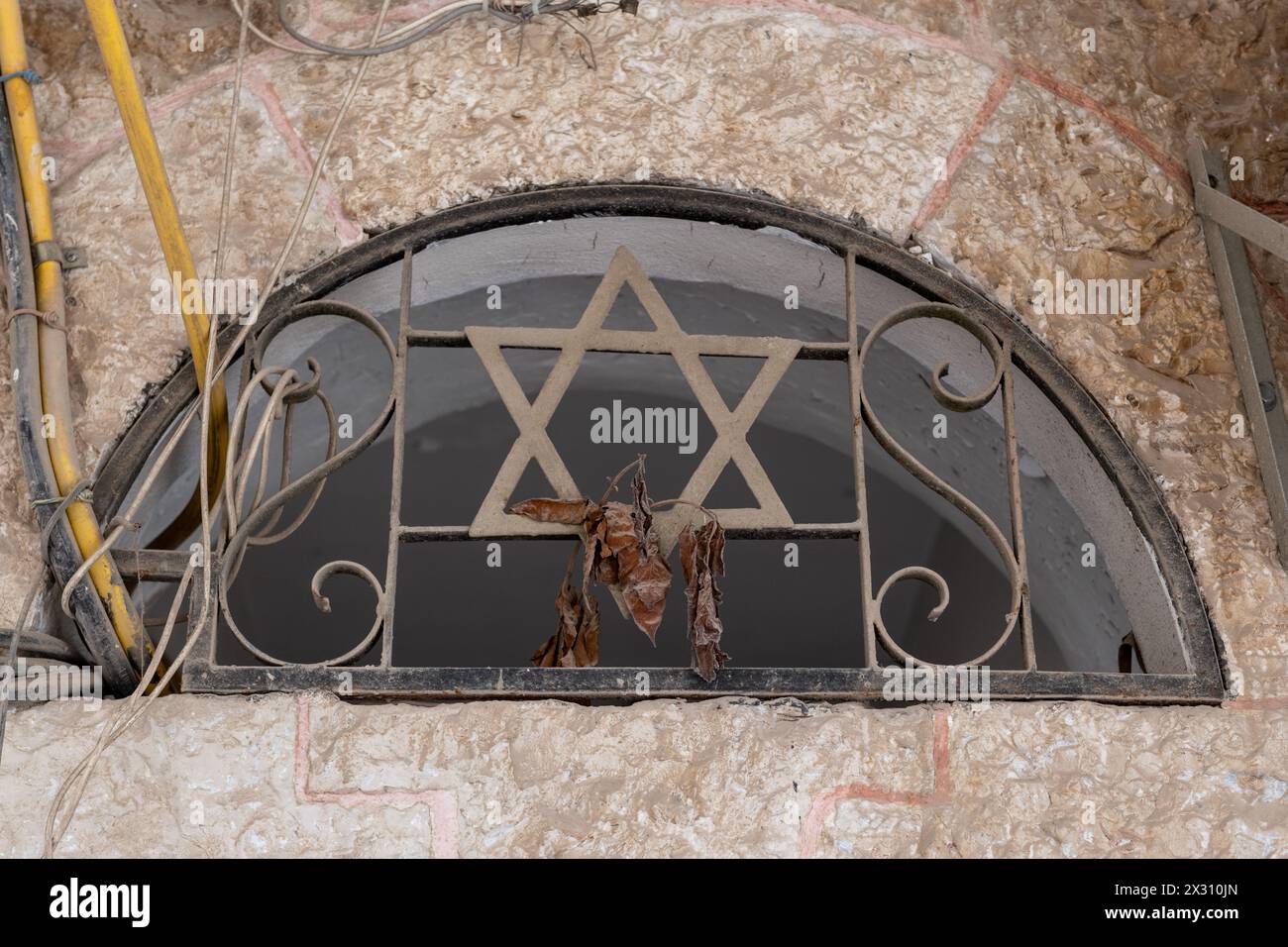 Come finestra di un centro commerciale in un vecchio palazzo di Gerusalemme nel quartiere di Mea She'arim con una griglia di metallo e la stella ebraica di David. Foto Stock