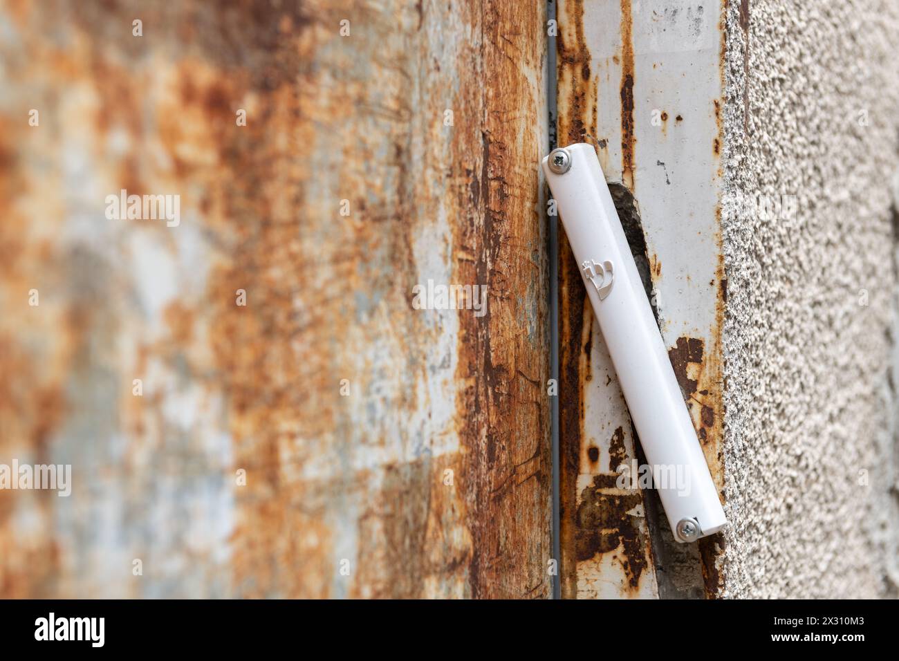 Un semplice caso bianco di mezuzah in plastica che tiene un piccolo pezzo di pergamena con la preghiera di Shema Yisrael, attaccato a una porta nella Mea She'arim nei Foto Stock