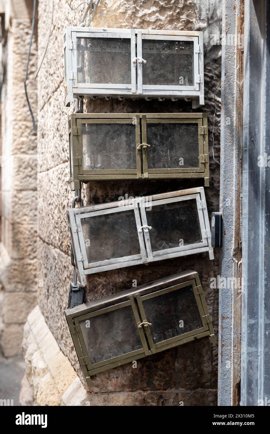 Quattro alloggiamenti vuoti in vetro per menorah di Hanukkah attaccati a un muro di pietra fuori da un edificio di appartamenti di Gerusalemme nel quartiere di Mea She'arim. Foto Stock