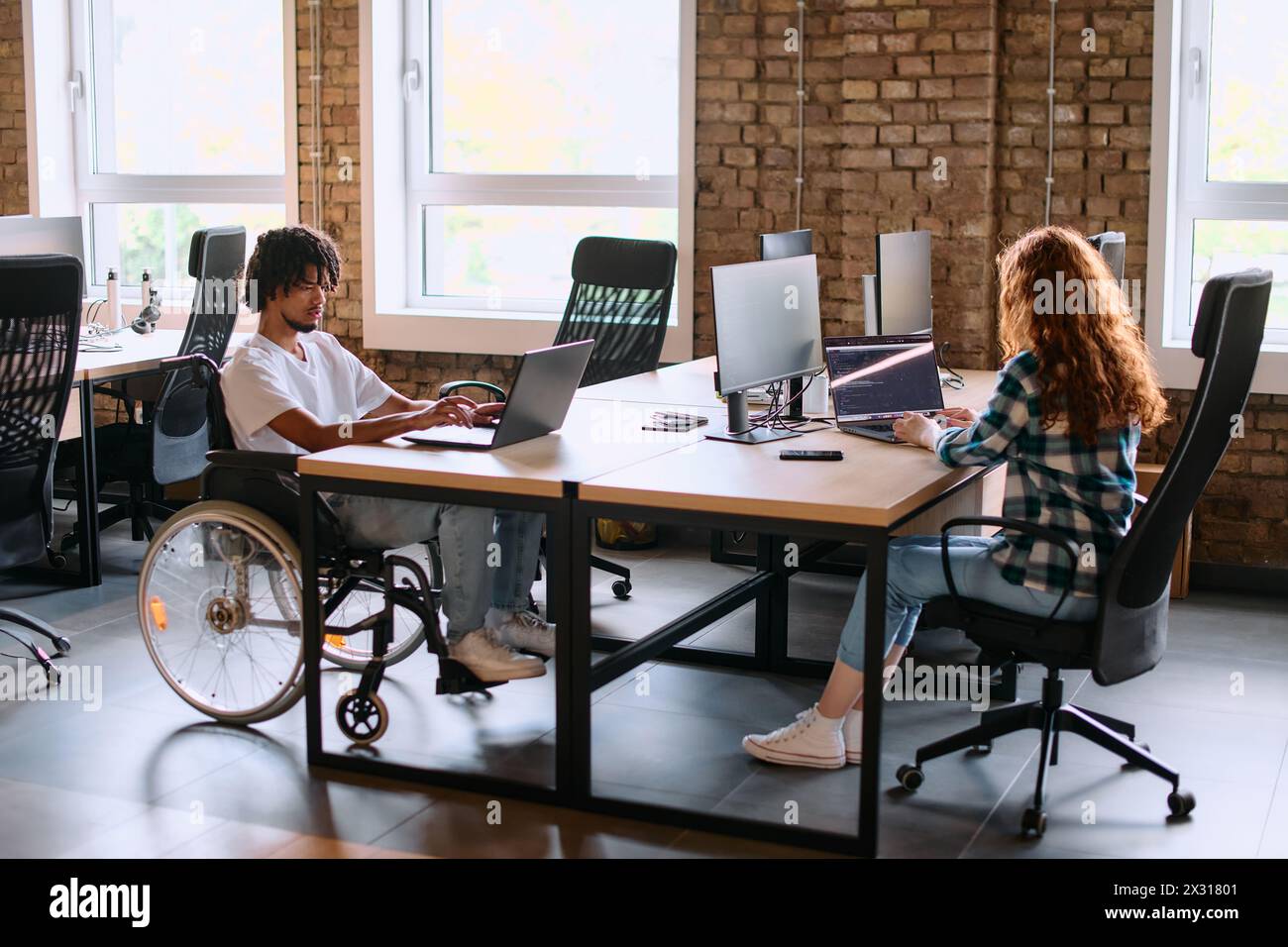 Un gruppo eterogeneo di professionisti aziendali collabora in un moderno centro di coworking startup, utilizzando un mix di strumenti cartacei e tecnologici Foto Stock