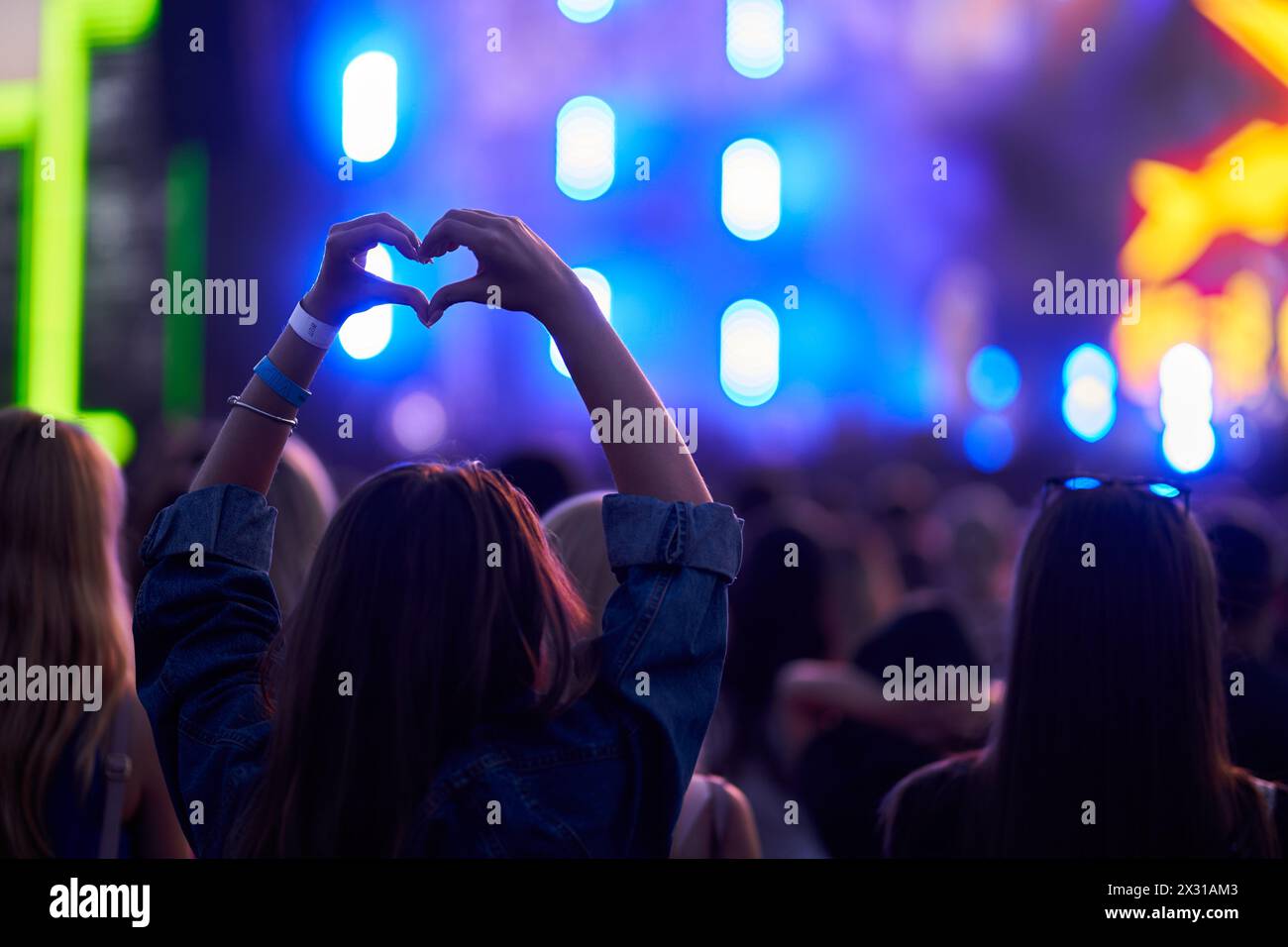 Le lancette sagomate danno forma al cuore durante la vivace festa della musica. Il pubblico gode di concerti dal vivo e luci colorate sullo sfondo. Atmosfera festosa, fan Foto Stock