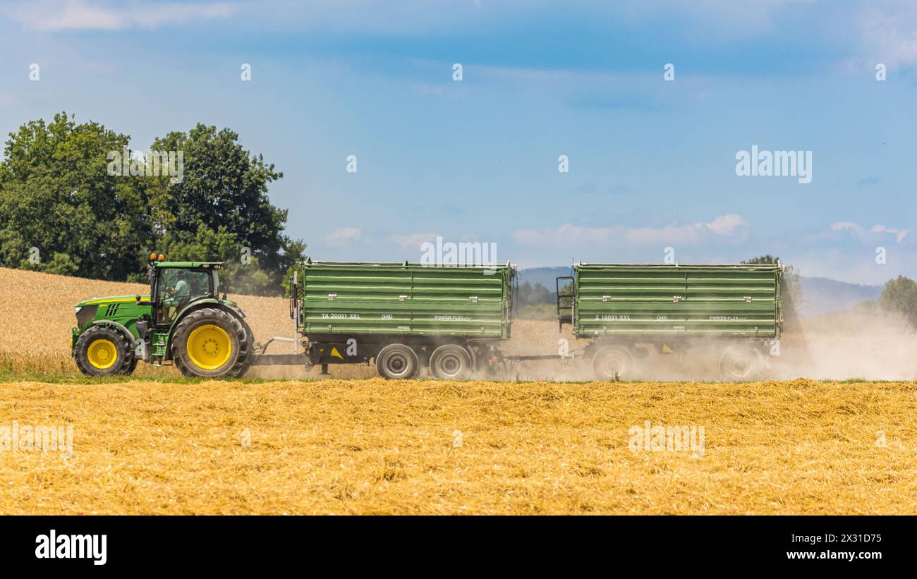Ein Landwirt fährt mit seinem John Deere Traktor und zwei Anhängern auf einem Feld im Zürcher Unterland. Die Trockenheit ist in diesem Sommer langanha Foto Stock
