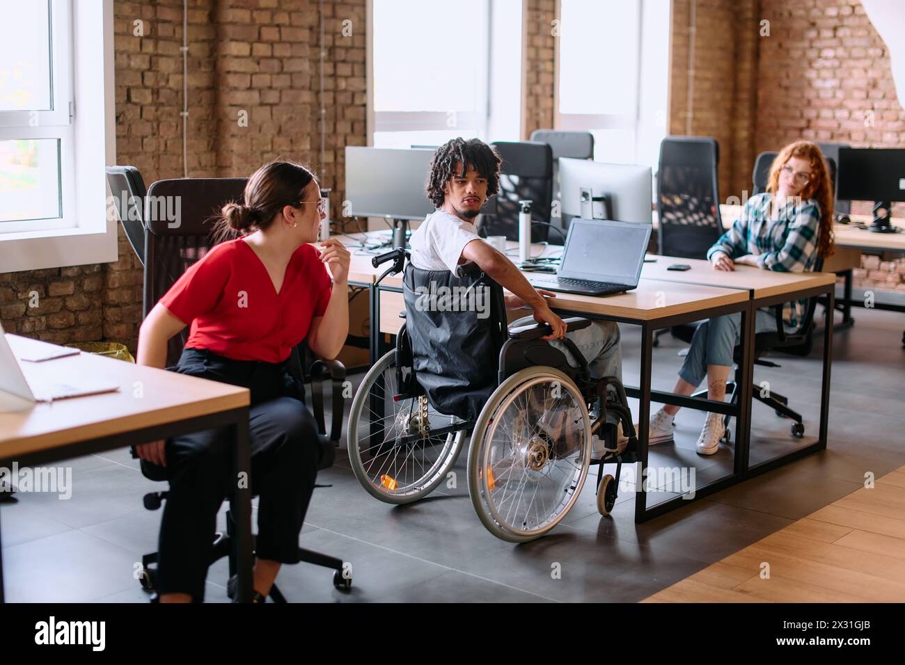 Un gruppo eterogeneo di professionisti aziendali collabora in un moderno centro di coworking startup, utilizzando un mix di strumenti cartacei e tecnologici Foto Stock