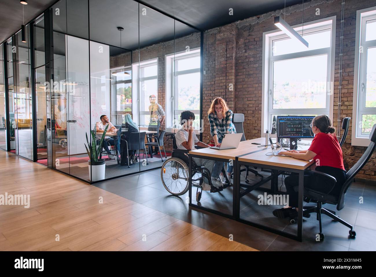 Un gruppo eterogeneo di professionisti aziendali collabora in un moderno centro di coworking startup, utilizzando un mix di strumenti cartacei e tecnologici Foto Stock