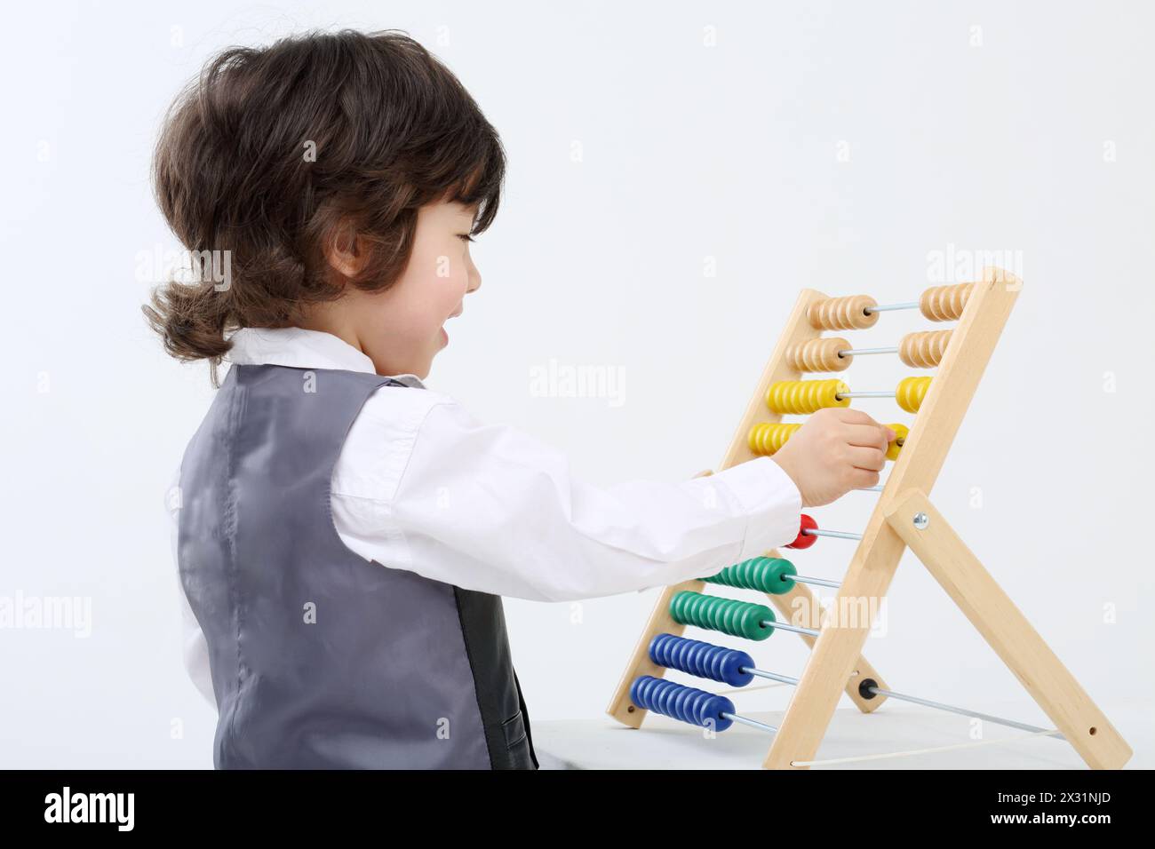 Il piccolo ragazzo felice in gilet gioca con abaco colorato in uno studio bianco. Foto Stock