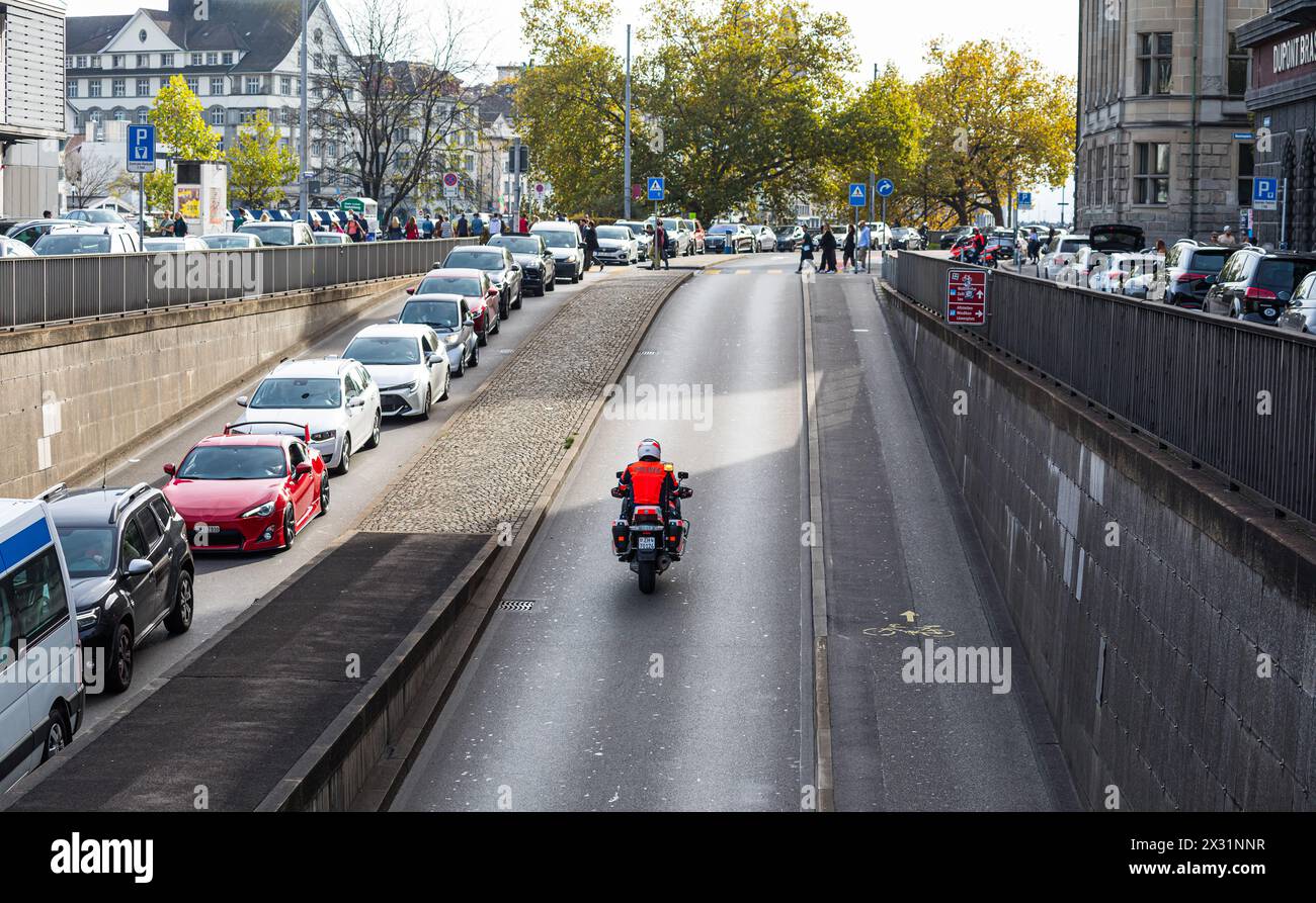 Auf der einen Seite staut sich der Verkehr in der Stadt Zürich. Auf der anderen Seite fährt ein Polizist der Stadtpolizei Zürich mit seinem Motorrad. Foto Stock