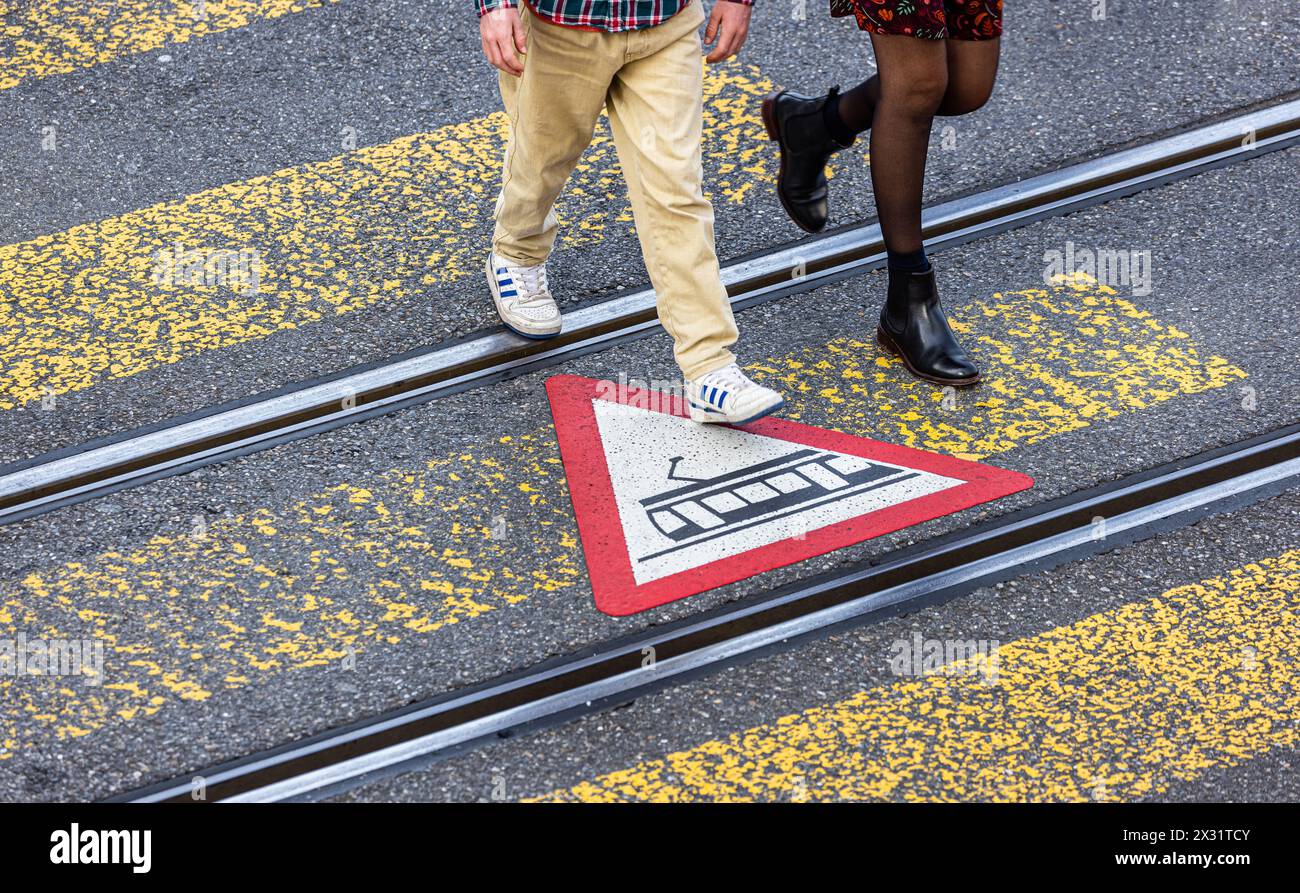 Fussgänger werden mittels Gefahrensymbolen auf dem Boden beim überqueren der Strasse über den Fussgängerstreifen vor der Strassenbahn gewarnt. (Zürich Foto Stock