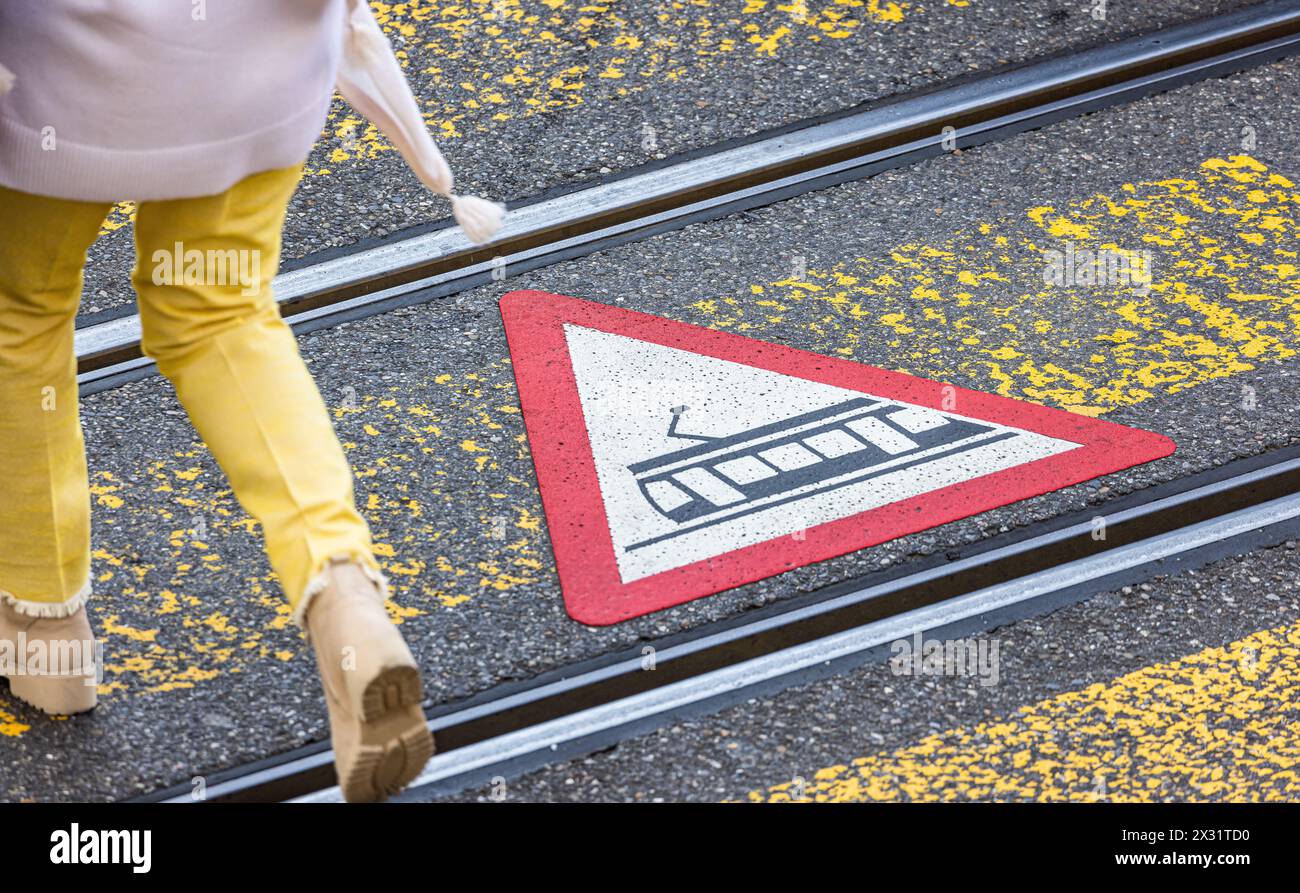 Fussgänger werden mittels Gefahrensymbolen auf dem Boden beim überqueren der Strasse über den Fussgängerstreifen vor der Strassenbahn gewarnt. (Zürich Foto Stock